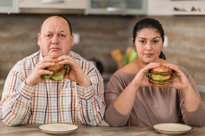 Coppia sovrappeso mangia hamburger