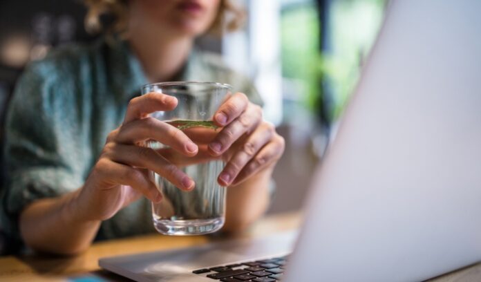 donna tiene bicchiere acqua computer