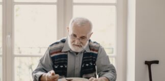 anziano seduto a tavola mangia minestra