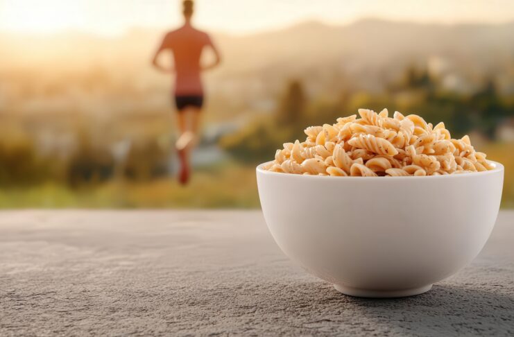 Piatto di pasta in primo piano e persona che corre in secondo piano