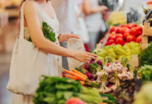 Persona che fa la spesa al supermercato, scegliendo verdure come ravanelli e carote