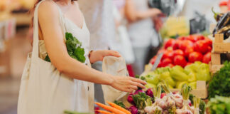 Persona che fa la spesa al supermercato, scegliendo verdure come ravanelli e carote
