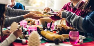 Persone intorno a un tavolo che mangiano. Indica convivialità