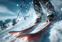 Nutrizione negli sport invernali: un approfondimento, aspettando il 20° Forum di Nutrizione Pratica Dettaglio dinamico di una discesa con gli sci che alzano nuvole di neve in alta montagna.