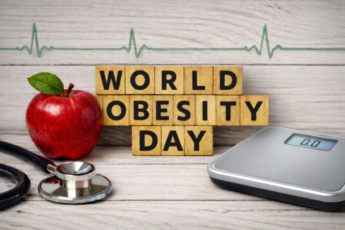 Scritta World obesity day con una mela e una bilancia